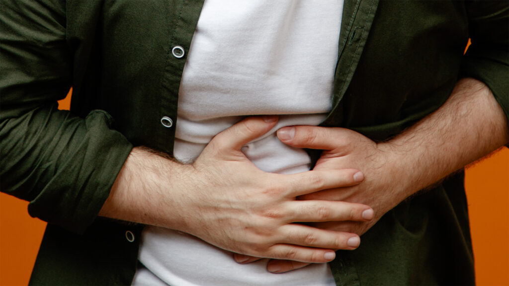 Man showing visible discomfort from common gut symptoms like bloating and abdominal pain, illustrating the physical impact of digestive imbalance.